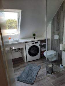 a bathroom with a washing machine and a toilet at Villa Mariensiel 2OG li in Sande