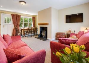 a living room with two red couches and a fireplace at Station Masters Cottage - Ravenglass in Ravenglass