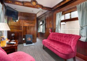 a living room with a red couch and a fireplace at Irt Pullman Carriage in Ravenglass