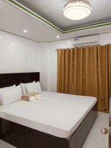 a large bed in a room with a ceiling at KMJ SUITES in General Luna