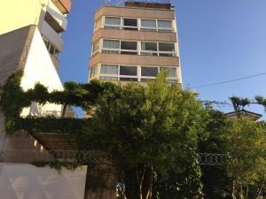a tall building with trees in front of it at Apartamento Manfroi in Bento Gonçalves