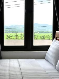 a bedroom with a bed and two windows with a view at Happy field homestay in Phong Nha