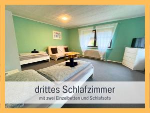 Attraktives Ferienhaus im Grünen في فالكنزيه: غرفة نوم بجدران خضراء وسريرين وطاولة