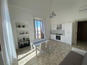 a white kitchen with a table and chairs in a room at Il Conte - Villa Gigia in Adelfia