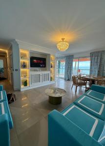 un soggiorno con sedie blu e TV di Annabel's Suite Apartament a Roquebrune-Cap-Martin
