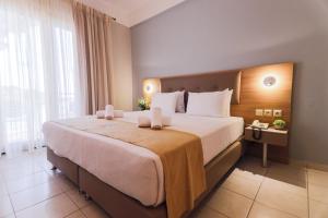 a bedroom with a large bed and a large window at Tosca Beach Hotel in Paleo Tsifliki