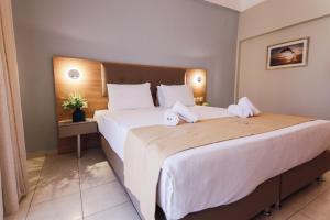 una habitación de hotel con una cama grande con sábanas blancas en Tosca Beach Hotel en PalaiónTsiflíkion