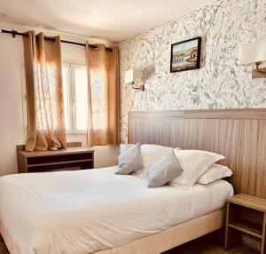 a bedroom with a bed with white sheets and pillows at Hotel Les Palmiers En Camargue in Saintes-Maries-de-la-Mer