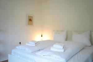 een wit bed met witte lakens en kussens erop bij City Apartment in bester Lage in Wolfsburg