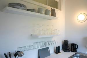 a kitchen with glasses on shelves above a sink at City Apartment in bester Lage in Wolfsburg