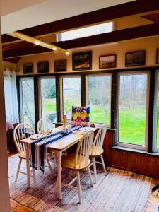 a dining room with a table with chairs and windows at Altja Villa-Cottage with sauna in Altja