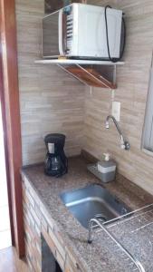 a kitchen counter with a sink and a microwave at Toca da Garoupa in Laguna