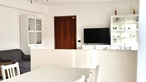 Sala de estar blanca con TV y mesa en K03 - Castelfidardo, ampio quadrilocale comodo ai servizi, en Castelfidardo