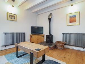 a living room with a wood stove and a tv at Oofoos Barn in Helston