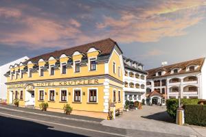 a yellow building on a street next to two buildings at Genussgasthof & Hotel beim Krutzler in Heiligenbrunn