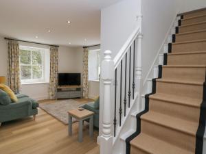a living room with stairs and a tv at Dalegarth Hall Farm Cottage 2 in Holmrook