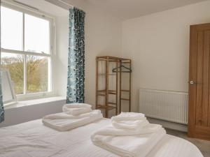 una habitación con 3 toallas blancas en una cama en Dalegarth Hall Farm Cottage 2, en Holmrook