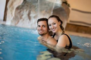 a man and a woman in a swimming pool at Genussgasthof & Hotel beim Krutzler in Heiligenbrunn