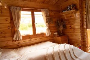 ein Schlafzimmer mit einem Bett in einem Blockhaus in der Unterkunft Cozy wood hut on the farm in Třebívlice