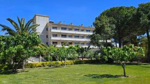 a building in the middle of a park with trees at Apartamentos La Masia in L'Estartit