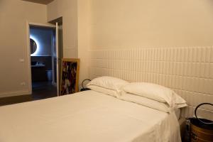a bed with white sheets and pillows in a room at Ginevra Boutique Rooms - Palazzo Leosini - Residenze D'Epoca in LʼAquila