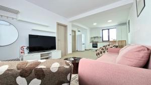 sala de estar con sofá rosa y TV en X rent apartment en 1 (Prim) Decembrie