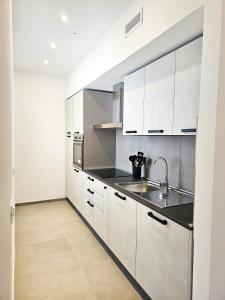 a kitchen with white cabinets and a sink at Bassa Marea in Grottammare