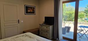 Dormitorio con cama y tocador con TV en Le Miroir des Etoiles, en Pomport