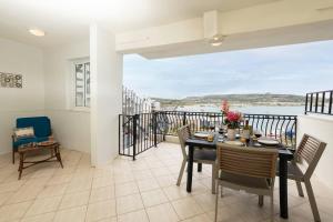 a dining room with a table and chairs on a balcony at GhadiraBay seafront with sea views by Homely in Mellieħa