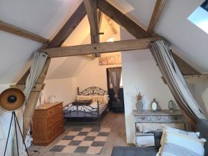 um quarto no sótão com uma cama e uma cómoda em le gîte au pied des chevaux em Baugé