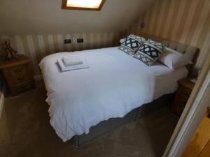 een slaapkamer met een wit bed met kussens erop bij The Moorings in Tarbert