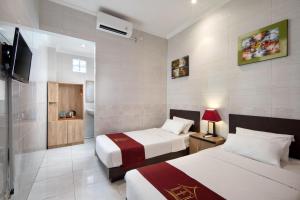 a hotel room with two beds and a television at Angkul Angkul Beach Inn Kuta by Kamara in Kuta