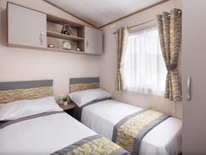 a room with two beds and a window at SBL38 Caravan at Camber Sands - quiet location in Camber