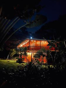 une maison éclairée la nuit dans l'établissement Mineral River Eco Village, à Upala