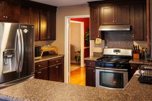 夏洛特的住宿－In the heart of the QC!，厨房配有木制橱柜和不锈钢冰箱。
