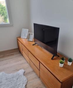 a flat screen tv sitting on top of a wooden dresser at Appartement Mers les Bains à deux pas de la plage. in Mers-les-Bains