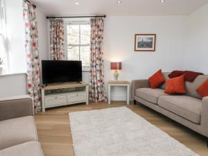 sala de estar con sofá y TV de pantalla plana en Dalegarth Hall Farm Cottage 1 en Holmrook