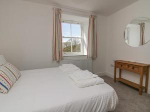 Schlafzimmer mit einem Bett mit einem Spiegel und einem Tisch in der Unterkunft Dalegarth Hall Farm Cottage 1 in Holmrook