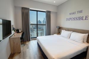 a bedroom with a bed and a desk and a window at Kingsgate Canal Hotel by Millennium in Dubai