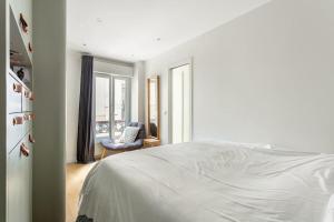 ein weißes Schlafzimmer mit einem Bett und einem Stuhl in der Unterkunft Bastille nest in Paris in Paris