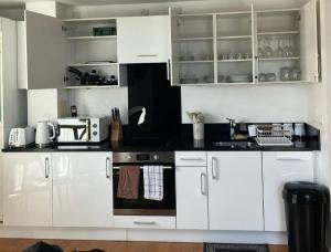 a kitchen with white cabinets and a stove at Heronsgate GH016 in London