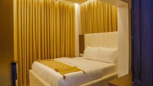 a bedroom with a bed with yellow curtains at LA FIFTHIN VILLA in Lekki
