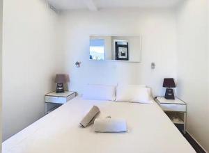 a white bedroom with a large white bed with two tables at Le Croisette I - 4 pers - Front de mer - Cannes in Cannes
