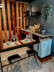 a kitchen with a counter with two chairs and a table with wine glasses at Apto Serrano in Igrejinha