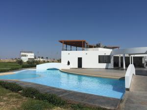 a swimming pool in front of a white house at Paracas Beach Vacation Rentals in Paracas