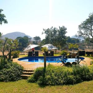 una piscina en un patio con mesa y sillas en River House Lodge en Malelane