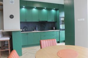 a kitchen with green cabinets and a table at Apartament przy Zodiaku in Mrągowo