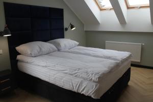 - une chambre dotée d'un grand lit avec des draps et des oreillers blancs dans l'établissement Apartament przy Zodiaku, à Mrągowo