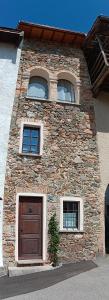 Antica torre del castello Casa Ceresiana في Carabietta: مبنى حجري مع نافذتين وباب