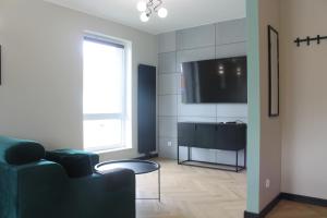 - un salon avec un canapé et une télévision dans l'établissement Apartament przy Zodiaku, à Mrągowo